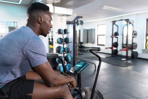 African american man resting on air bike in modern gym after intense cardio workout