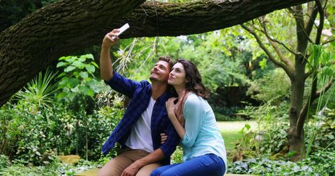 Couple Enjoying Nature While Taking Selfie in Lush Park