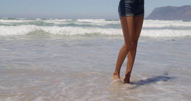 Woman's Legs in Shorts Standing on the Beach Near Waves - Download Free Stock Images Pikwizard.com