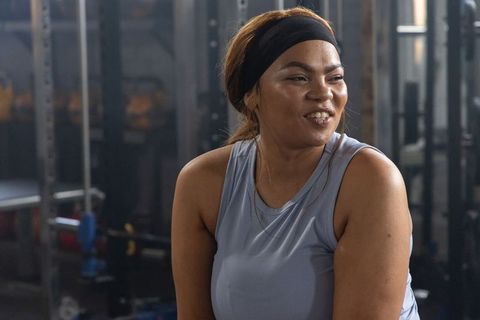 African american woman smiling after workout in gym with barbells and headband
