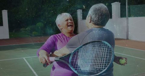 Happy Senior Couple Embracing on Tennis Court with Rackets