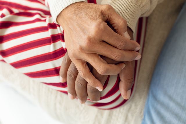 Close-up of happy senior diverse couple hands on top of each other. Authentic Senior Retired Life Concept