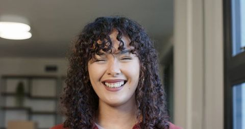 African american woman smiling with eyes nearly closed in cozy home office portrait with soft light