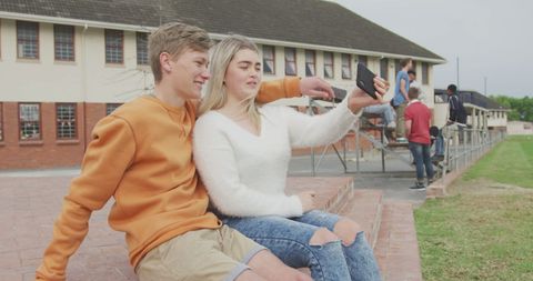 Teen Couple Taking Selfie Outdoors by School Building
