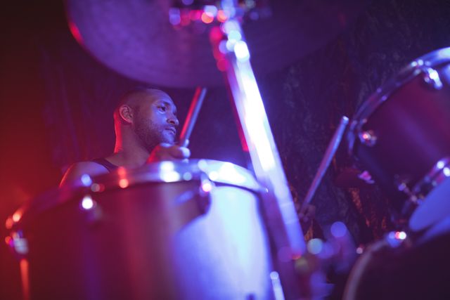 This image captures a male drummer performing at a music concert from a low angle, emphasizing the energy and passion of live music. Ideal for use in articles, blogs, and promotional materials related to music, concerts, live performances, and entertainment.