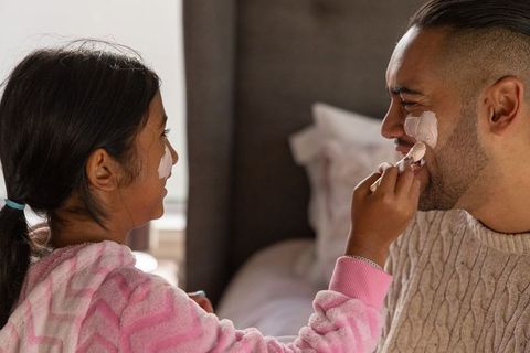 Father and daughter applying cream during playful skincare bonding morning routine