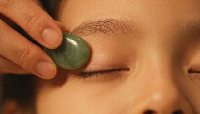 Close-up jade eye massage calming facial therapy for delicate skin and eye care