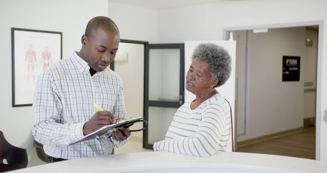 Male Nurse Taking Notes with Elderly Patient in Hospital Reception - Download Free Stock Images Pikwizard.com