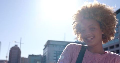 Sunlit African American Woman Smiling on Urban Street in Pink Sweater Backlit Portrait