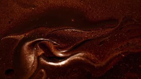 Rippling viscous chocolate folding and cooling in macro slow motion with glossy swirl