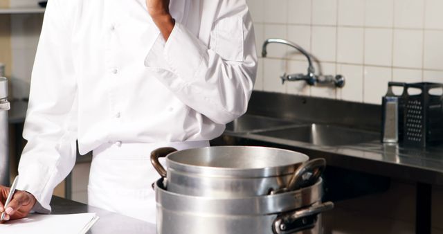 Chef cooking in commercial kitchen, wearing white uniform, busy culinary workspace - Download Free Stock Images Pikwizard.com