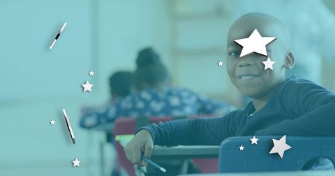 Smiling boy leaning on desk in classroom holding pencil with star overlays and copy space