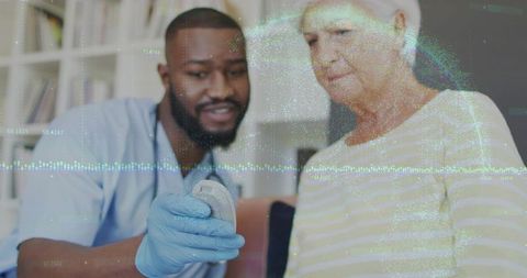 Nurse demonstrating hearing remote to elderly woman during home care visit