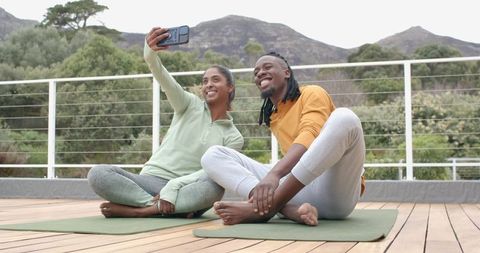 Diverse Couple Taking Selfie on Outdoor Yoga Mats on Mountain Deck