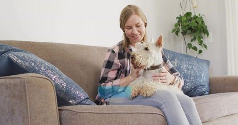 Woman Relaxing at Home with Terrier Dog on Cozy Sofa