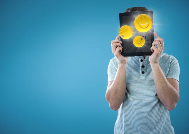 Person holding tablet over face displaying bright yellow smiling and sleep emojis with lens flares. Ideal for concepts of digital communication, humor, technology usage, expressing emotions digitally, and light-hearted creative projects.