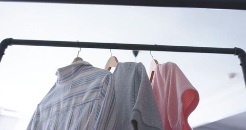 Hanging striped gray and pink garments on industrial pipe rail with wooden hangers retail