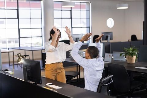 Dynamic office duo celebrating success with high five