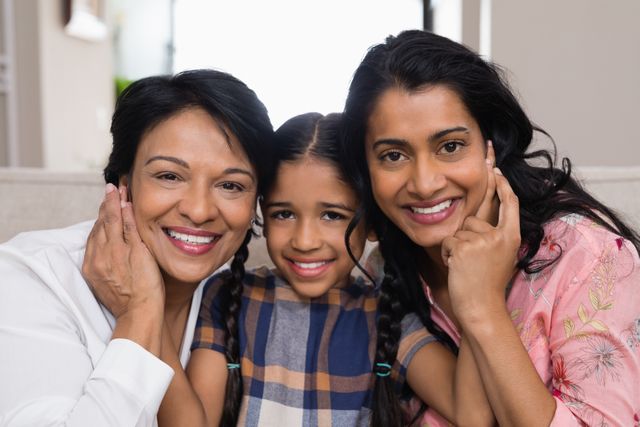 Three generations of women smiling and bonding at home. Ideal for use in family-oriented advertisements, articles on family dynamics, or promotional materials for family services. Highlights themes of love, togetherness, and generational connections.