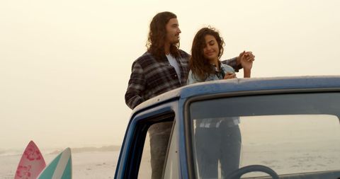 Young couple enjoying beach sunset by vintage car