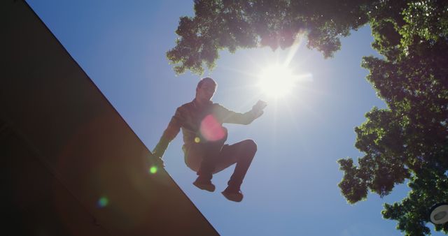 Man Parkouring on Building Roof Under Bright Sunlight - Download Free Stock Images Pikwizard.com