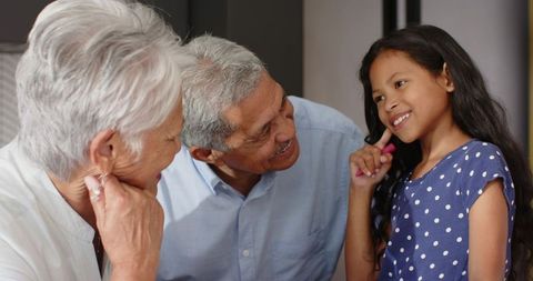 Grandparents Leaning In Smiling at Granddaughter in Polka Dot Dress Sharing Sweet Moment