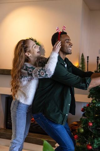 Cheerful Couple Decorating Christmas Tree in Cozy Home Interior