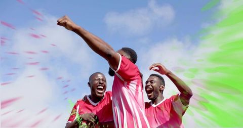 Celebrating soccer team throwing vibrant green and red powder on field, cheering with energy