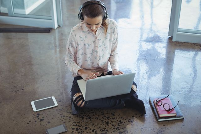 Entrepreneur wearing headphones while working on laptop at office floor