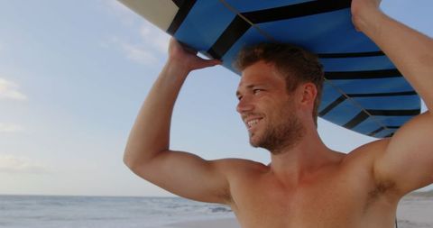 Shirtless Young Man Smiling Carrying Surfboard on Beach