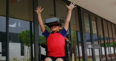 Joyful boy in wheelchair experiencing virtual reality at school