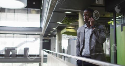 image shows an african american man in a suit using a cellphone in a sleek, modern office environment. digital circles and bars overlay suggest topics of digital transformation and technological progress. this can be used in contexts related to business communication, modern technology solutions, and innovation-in-business settings, or illustrating concepts of digital connectedness and corporate strategy.