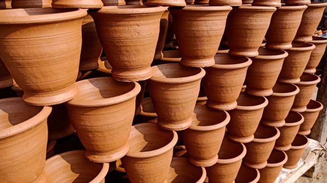 Stacking terracotta garden pots on wooden racks catching warm sunlight and rustic texture