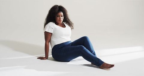 Confident woman in casual jeans in minimalist white studio
