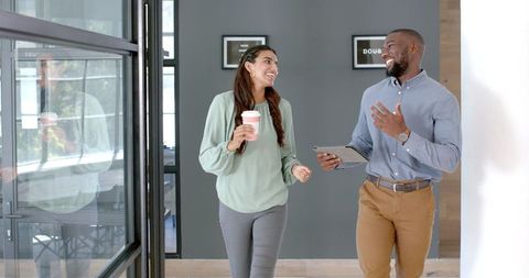 Colleagues Walking and Discussing Business with Tablet and Coffee