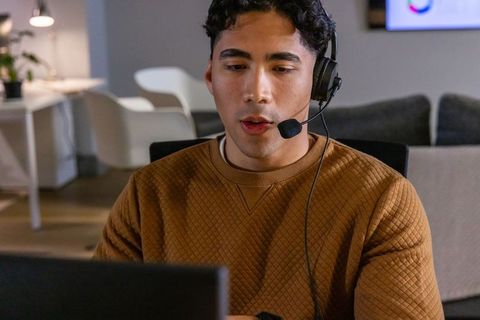 Remote customer support agent wearing headset working on laptop in modern office space
