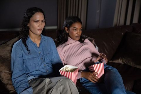 Female friends enjoying movie night at home with popcorn