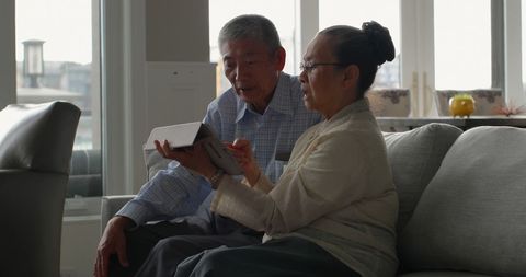 Senior Asian Couple Using Tablet in Cozy Living Room