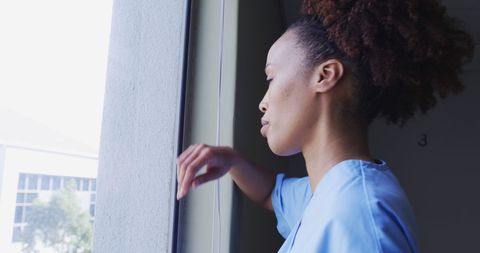 Pensive Female Healthcare Worker Reflecting by Hospital Window