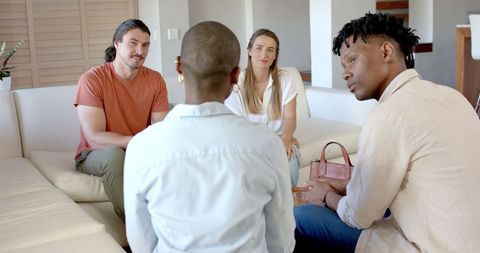 Friends conversing happily on comfortable sofa at home