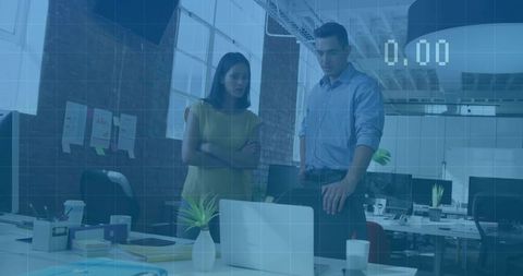 Modern office colleagues reviewing laptop in open-plan workspace