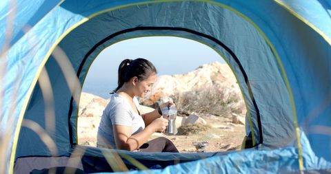 Woman Enjoying Morning Coffee While Camping in Mountain Tent