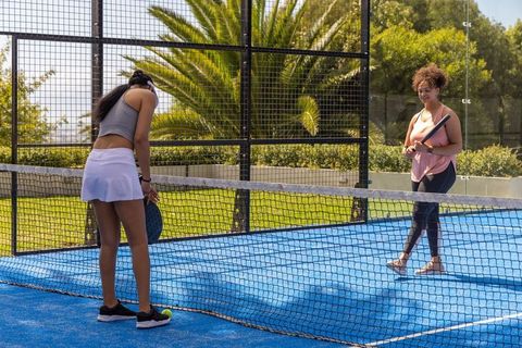 African american women playing padel on blue court holding rackets and ball