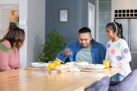 Family sharing cozy breakfast around wooden dining table with orange juice and warm smiles
