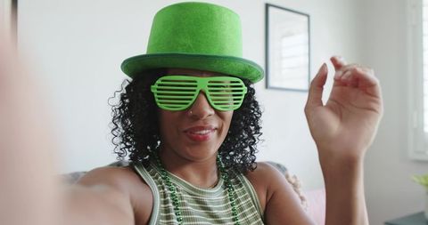 African american woman posing for selfie wearing green hat, shutter shades, beads