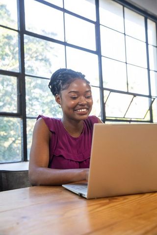 African American Woman Typing on Laptop in Bright Room