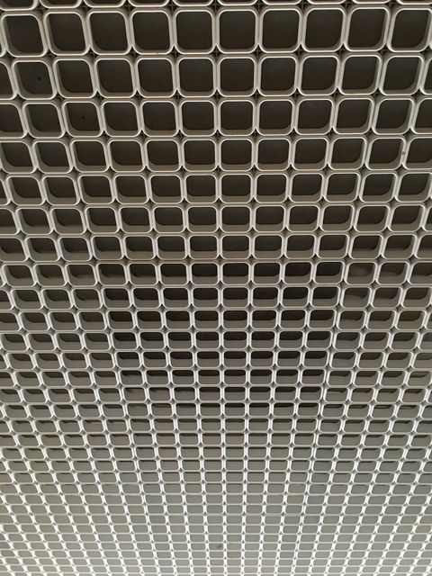 High-resolution photo showcasing square metal grid on a ceiling, ideal for industrial design projects. Can be used for backgrounds, presentations, and modern architectural showcases.