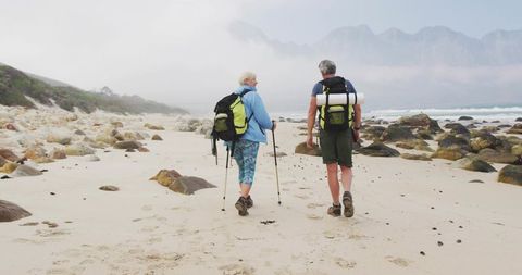 Senior Couple Trekking on Misty Rocky Shore