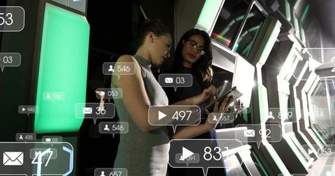 Businesswomen collaborating with augmented reality tablet in futuristic hexagonal corridor