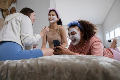 Diverse Friends Enjoying Relaxing Skincare Routine in Cozy Bedroom